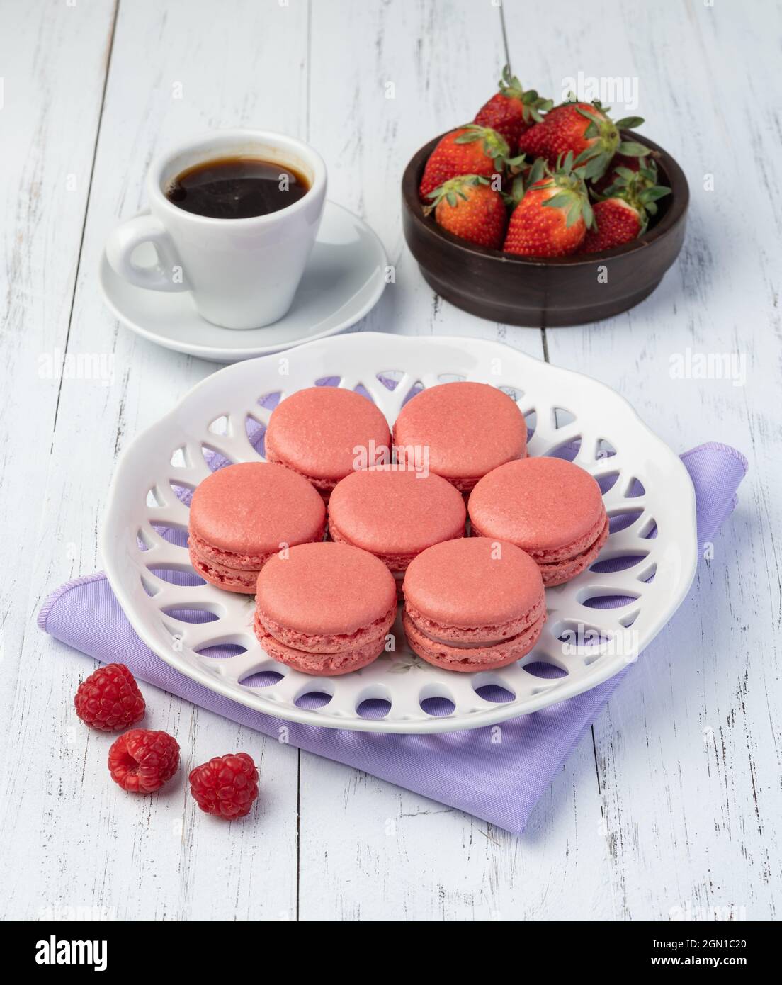 Macaron di Berry su un piatto con caffè su tavola di legno. Foto Stock