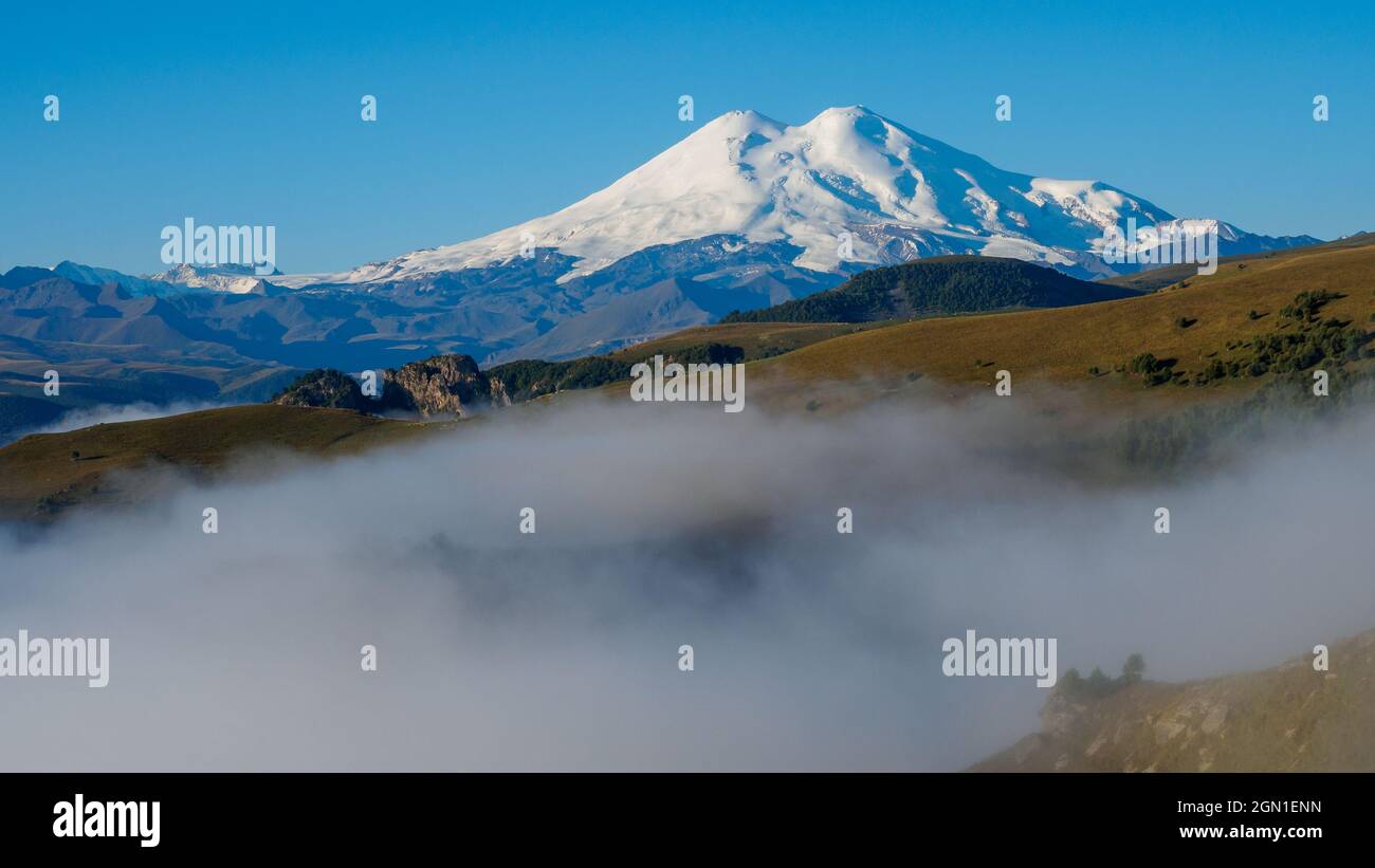 Misty autunno colline di fronte a lontano nevoso montagna Foto Stock