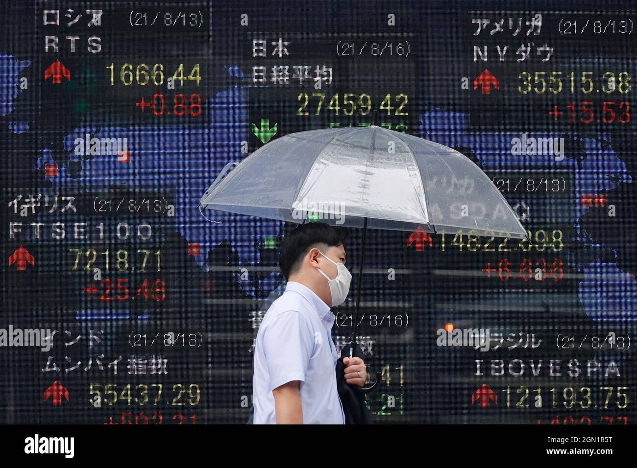 Tokyo, Giappone. 16 agosto 2021. Un uomo che tiene un ombrello cammina di fronte a un quadro elettrico che mostra Nikkei indice un brokerage a Tokyo. (Foto di James Matsumoto/SOPA Images/Sipa USA) Credit: Sipa USA/Alamy Live News Foto Stock