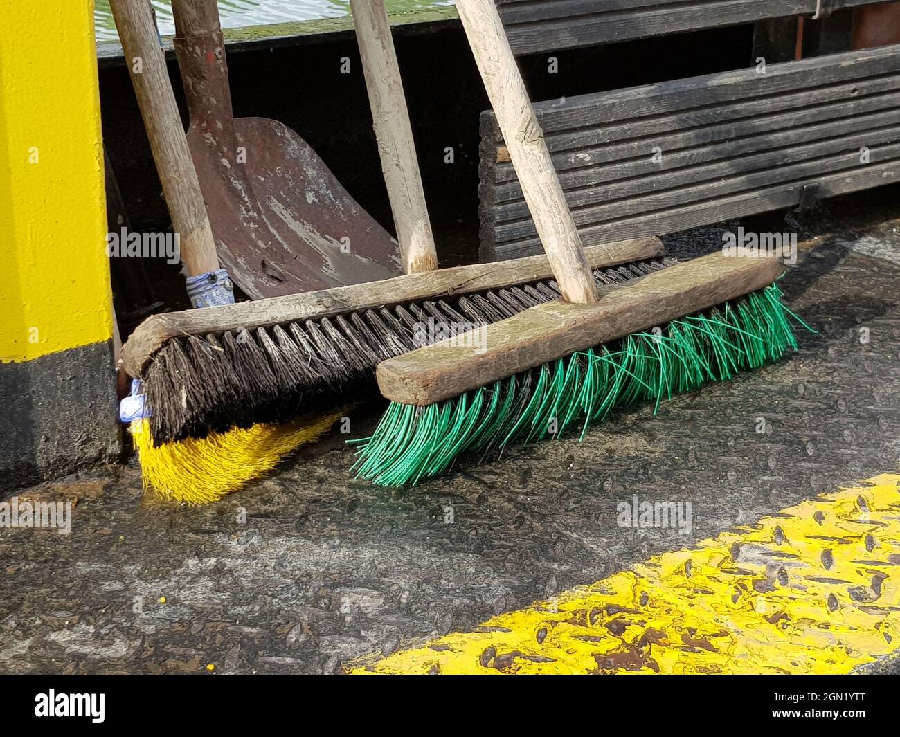 Primo piano delle vecchie scopa in legno sporco sul terreno metallico Foto Stock