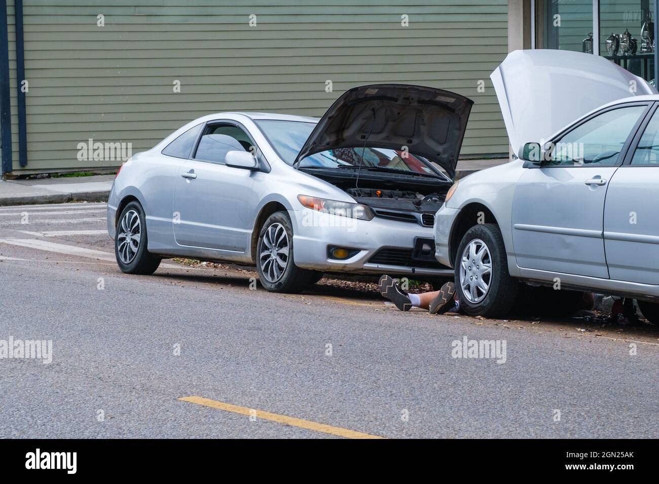 Persona effettua riparazioni auto su strada della città Foto Stock
