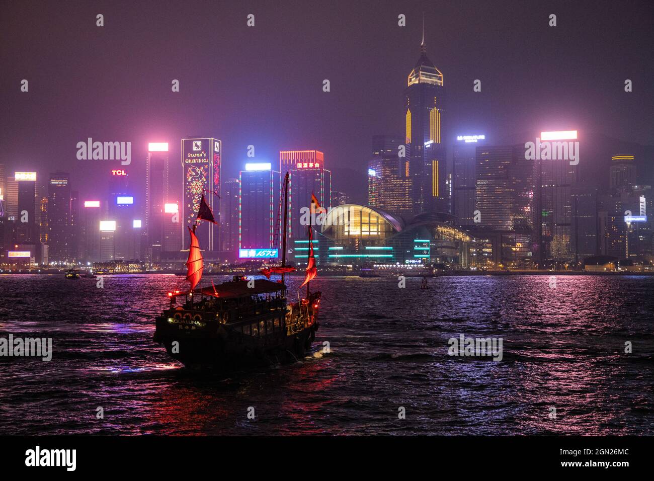 Tradizionale spazzatura che serve come barca turistica nel Victoria Harbour con lo skyline di Hong Kong dietro di esso di notte, Hong Kong, Hong Kong, Cina, Foto Stock