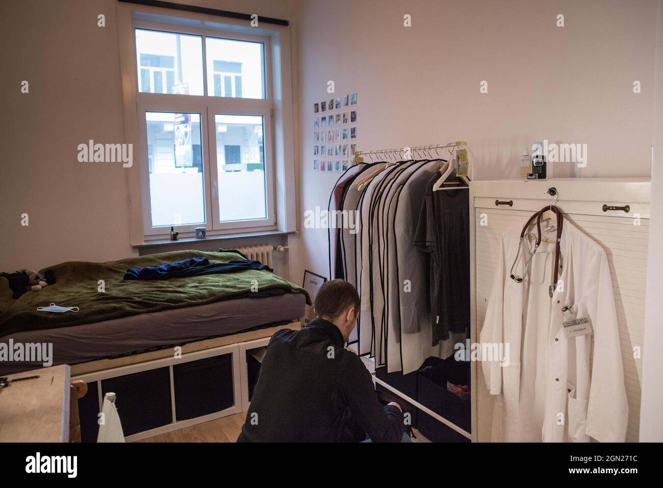 Hannover, Germania. 19 Settembre 2021. Luis, uno studente di medicina presso la Hanover Medical School, si schiaccia di fronte a un portabiti nella sua camera da letto nel suo appartamento studente. A destra, il suo cappotto bianco e lo stetoscopio si appendono su un armadio. Viene da Bielefeld e ha due flatmates femminili. (A dpa 'Online-PK on the housing situation of students in Germany') Credit: Eman Helal/dpa/Alamy Live News Foto Stock