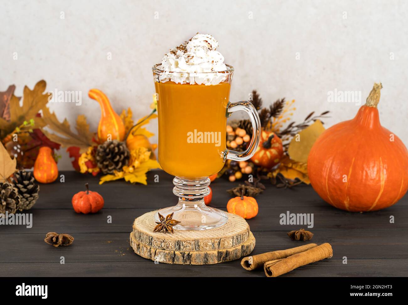 Spice latte di zucca, di stagione, dolce, calda bevanda autunnale. Frullato con panna montata. Sfondo in legno Foto Stock