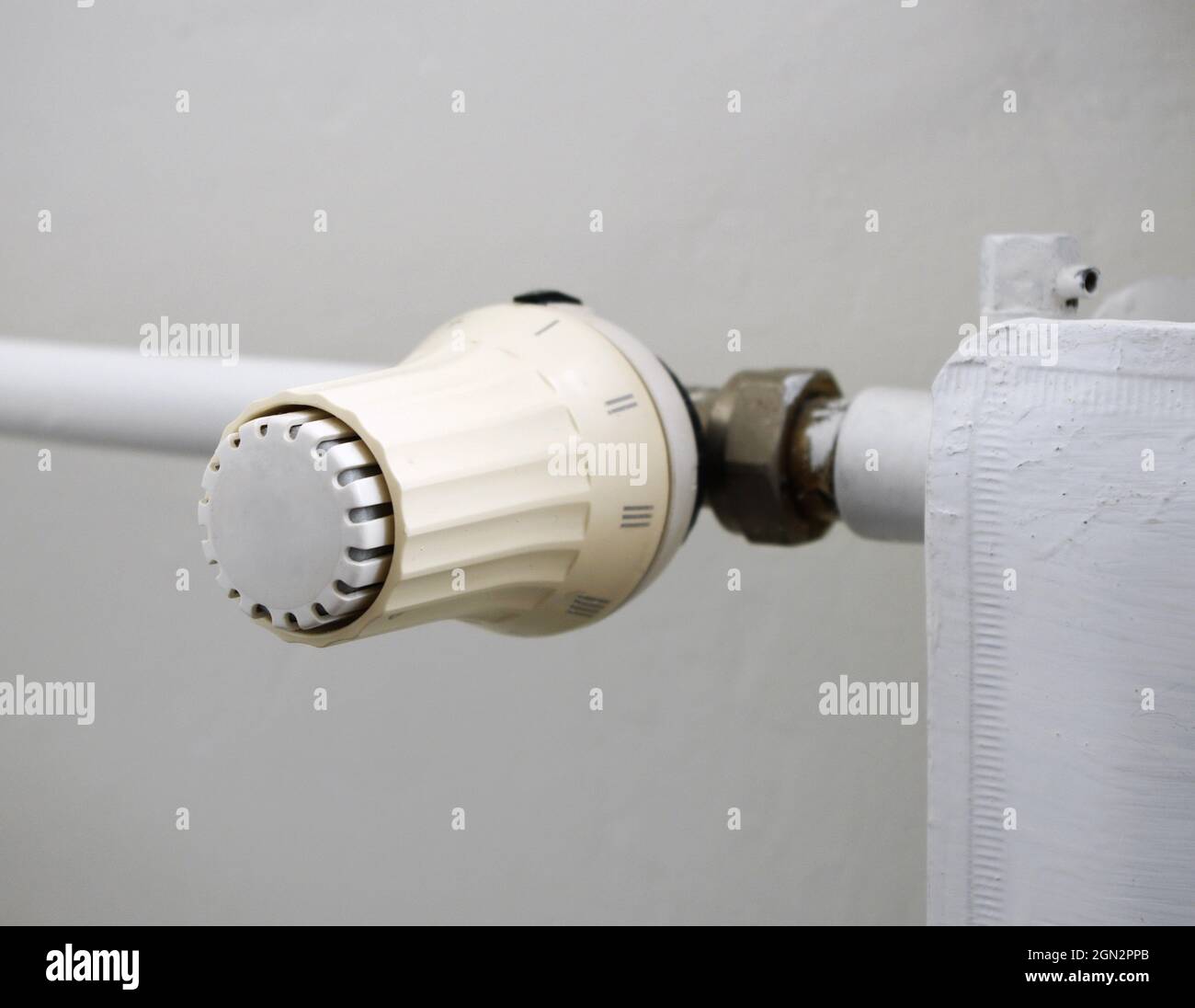 Prezzi del calore e concetto di crisi energetica. La manopola di regolazione della temperatura del radiatore di riscaldamento, il termostato, riduce i costi di riscaldamento. Foto Stock