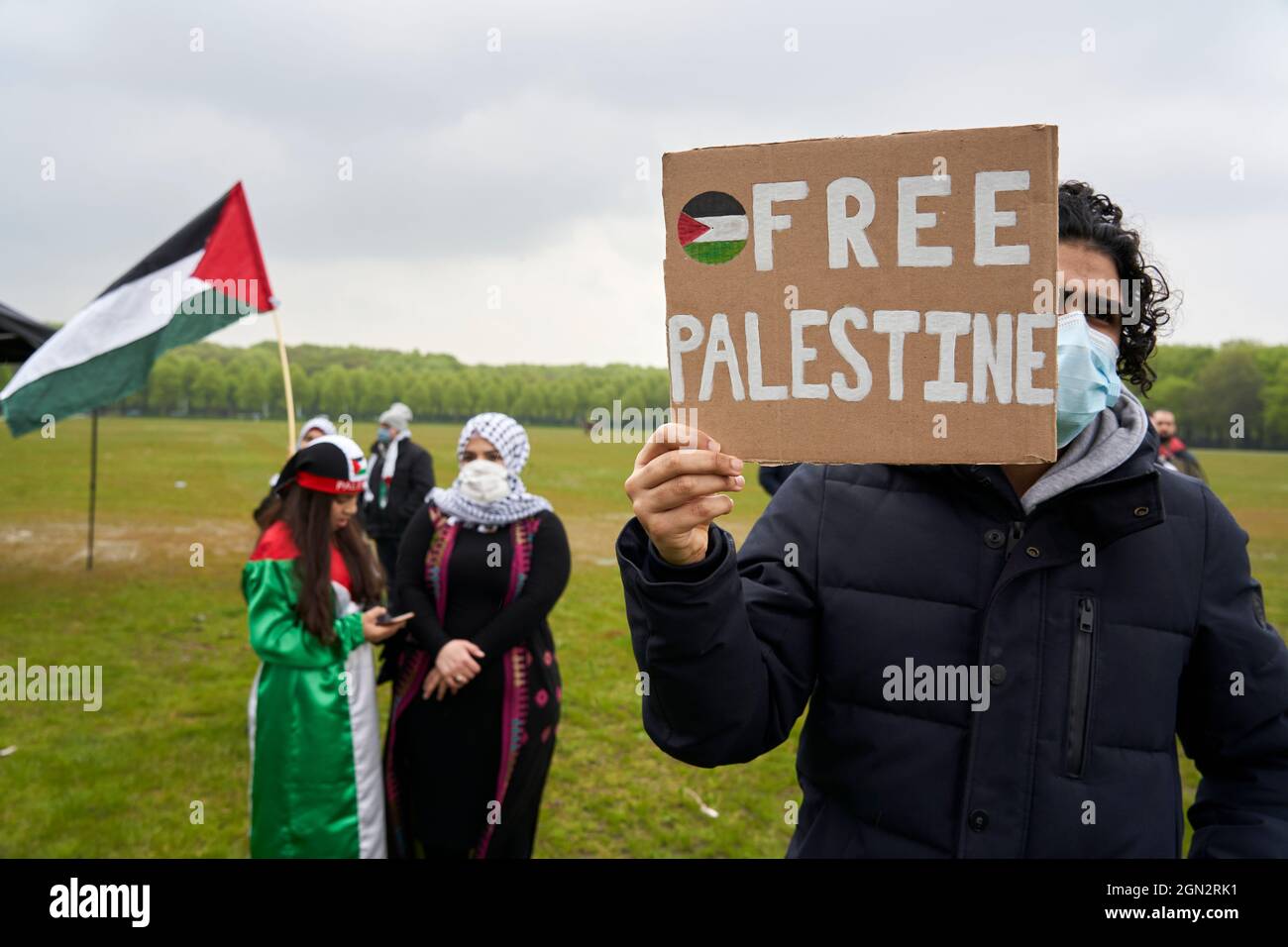 Un uomo con una bandiera partecipa a una manifestazione pro-palestinese. Foto Stock