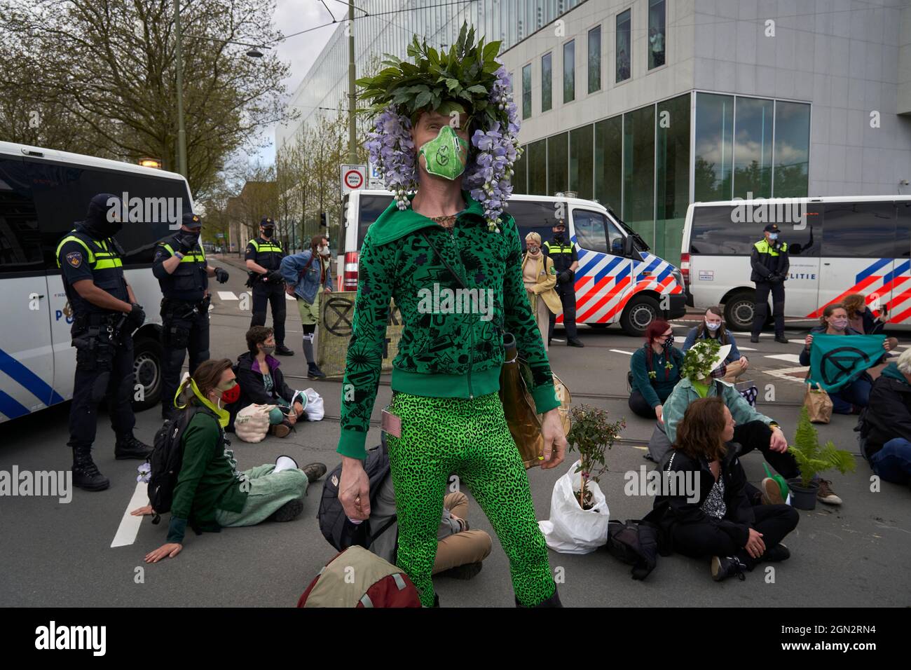 Un attivista di ONG partecipa alla protesta climatica indossando un costume con piante sulla testa. Foto Stock