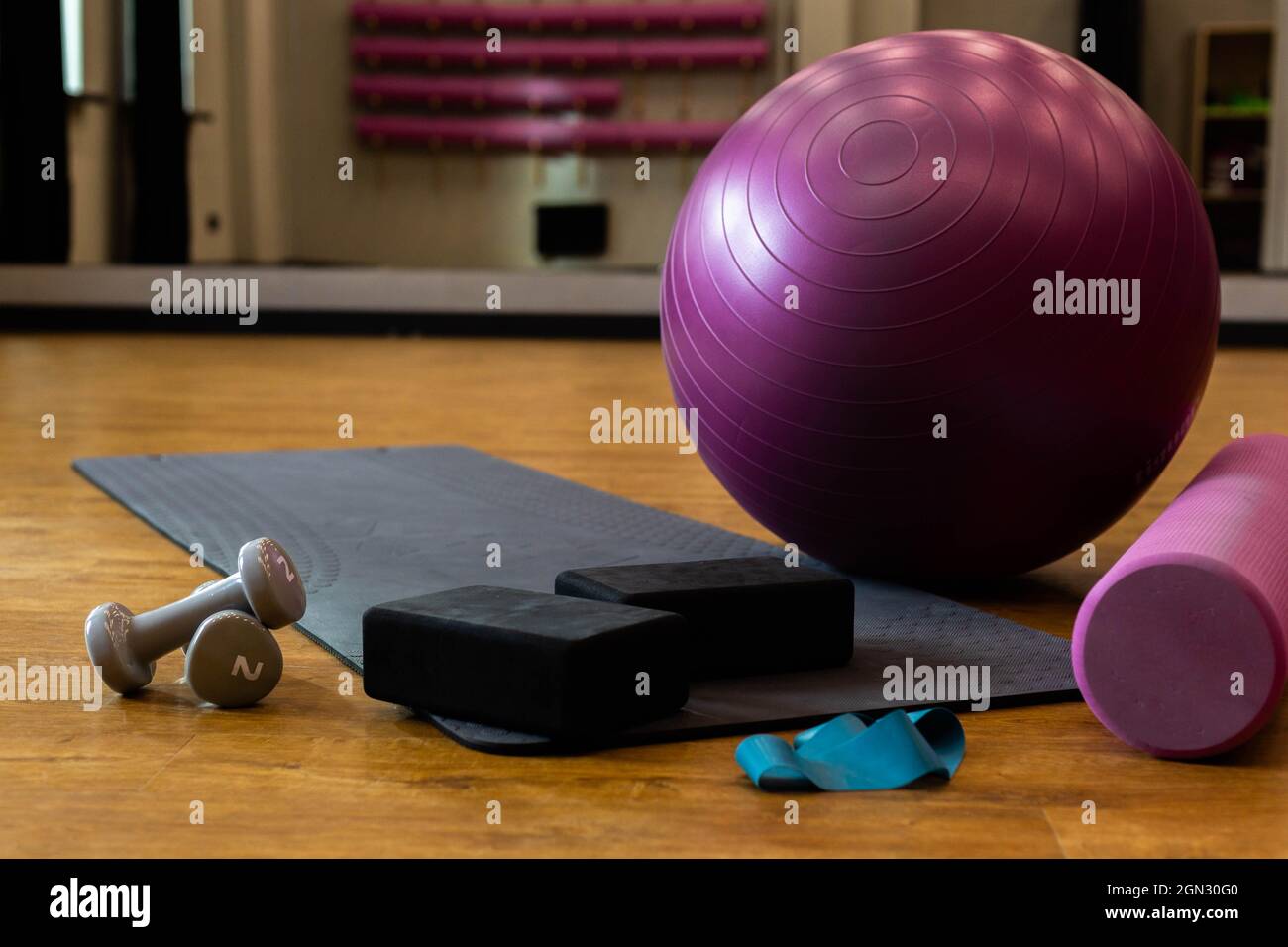 Set di attrezzature sportive con palla fitness e materassino yoga nella palestra sul pavimento Foto Stock