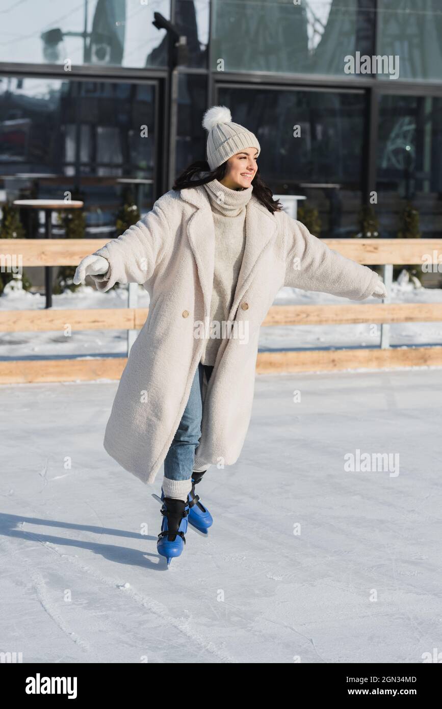 tutta la lunghezza della giovane donna felice in inverno cappello e  cappotto di pattinaggio su pista di ghiaccio Foto stock - Alamy