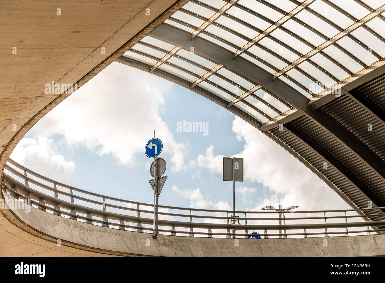 Basso angolo di strada curvilinea recintata con segnaletica stradale su pali sul cavalcavia Foto Stock