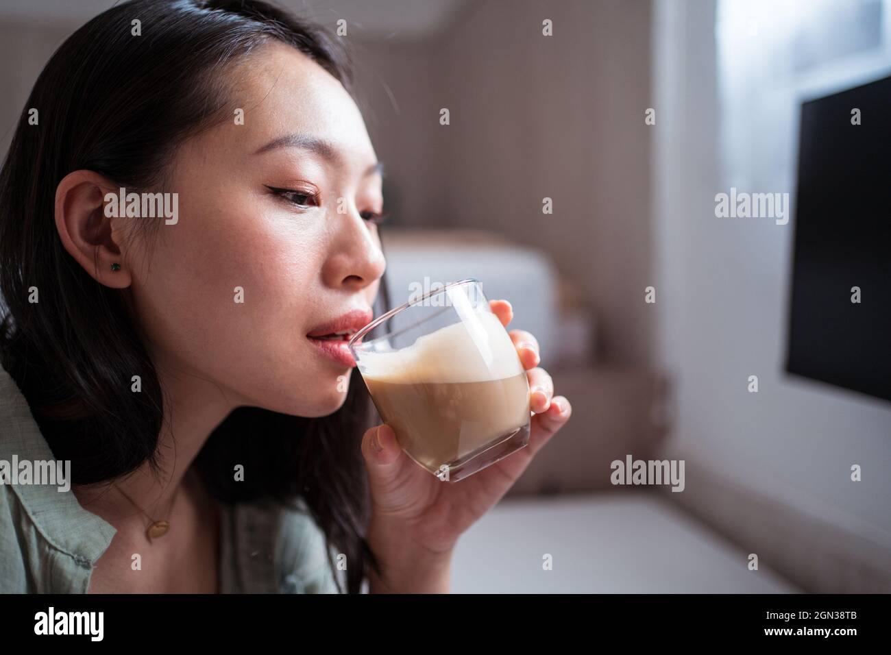 Vista laterale di giovani donne etniche blogger alla scrivania bere caffè a casa Foto Stock
