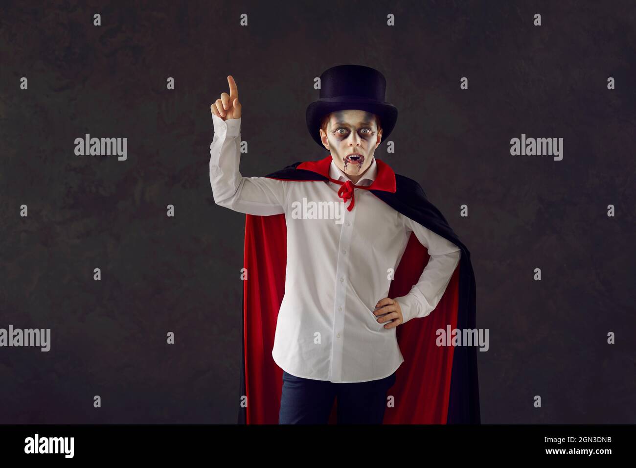 Ritratto di un bambino vestito come un vampiro per una festa di Halloween che punta il suo dito su Foto Stock