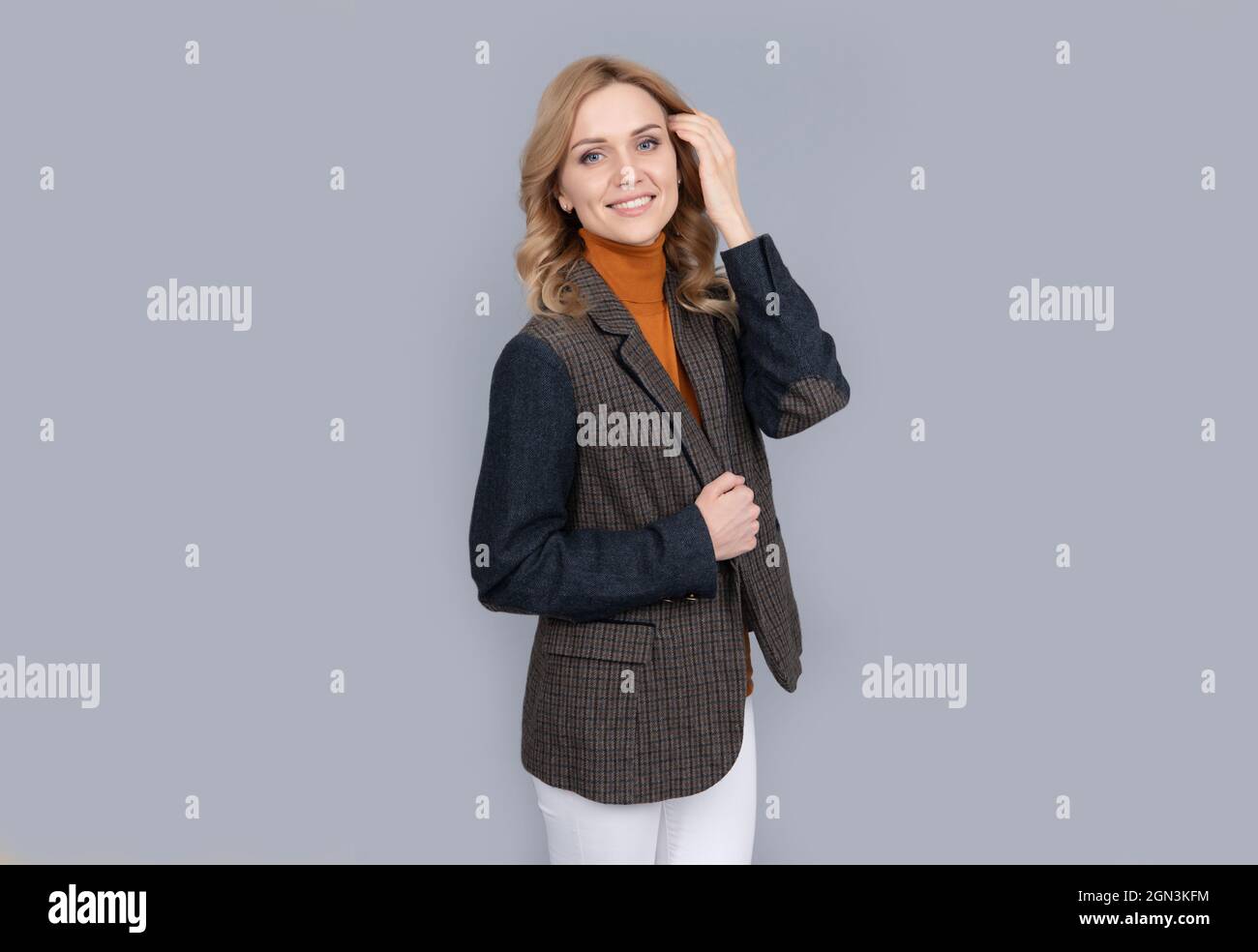 donna allegra in affari casual giacca britannica su sfondo grigio, bellezza Foto Stock