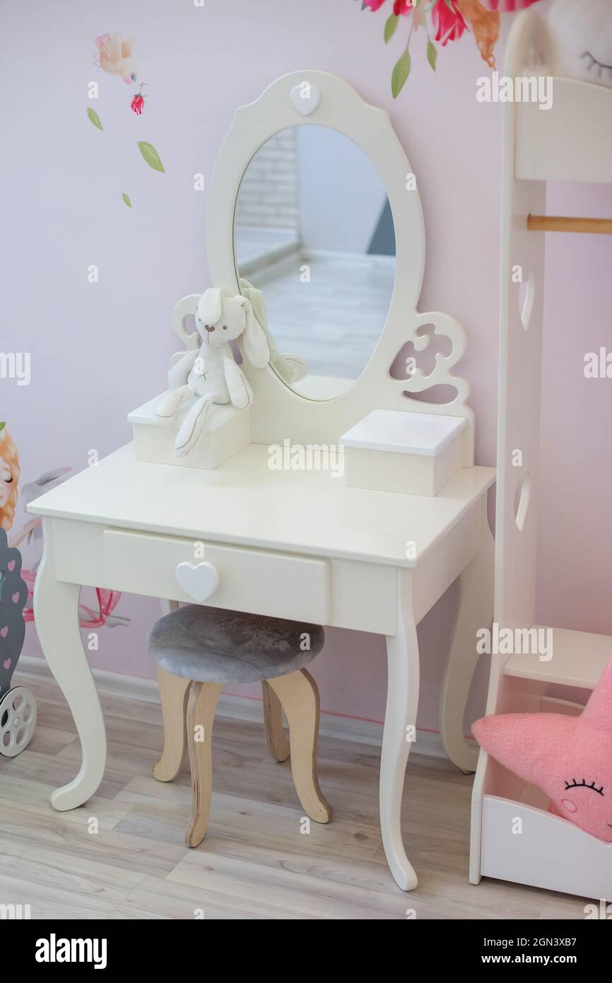 un elegante tavolo bianco per bambini con uno specchio ovale in camera Foto Stock