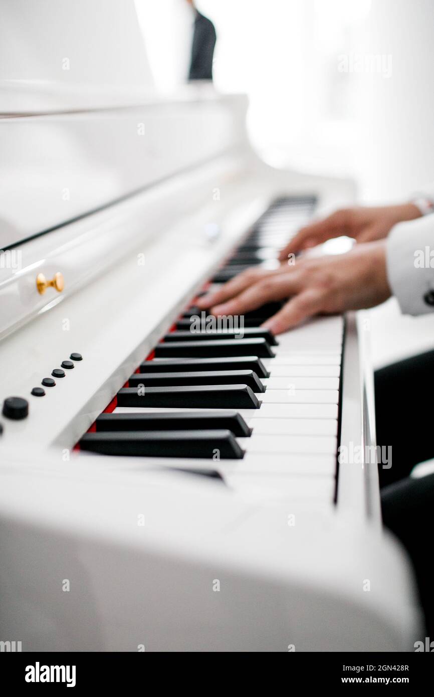 un pianista in abito bianco suona il pianoforte Foto Stock