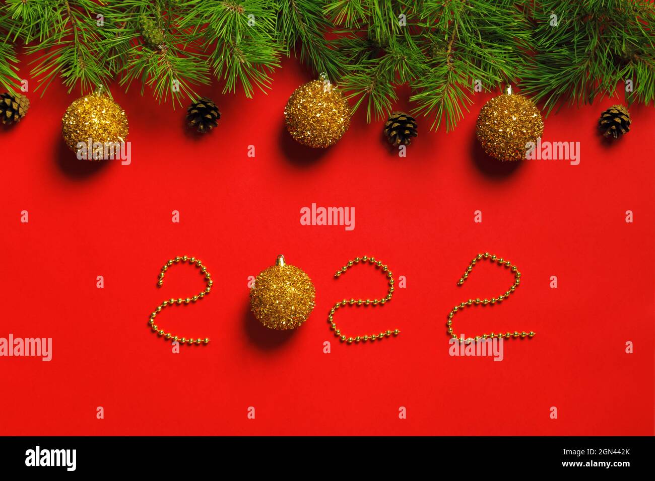Banner natalizio in rami di abete con coni in palline su sfondo rosso con iscrizione Capodanno 2022 Foto Stock