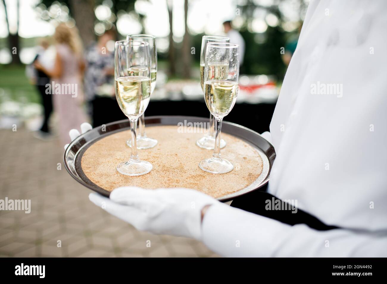 Bel giovane butler tenendo il vassoio in argento con due bicchieri di champagne Foto Stock