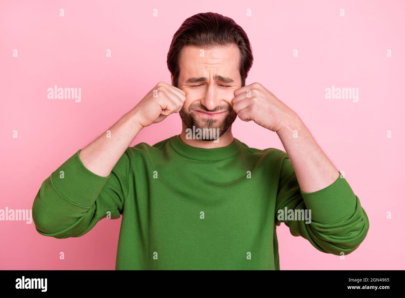 Foto di insoddisfatto moody persona chiuso occhi braccia salvietta lacrime indossare maglione isolato su sfondo rosa Foto Stock
