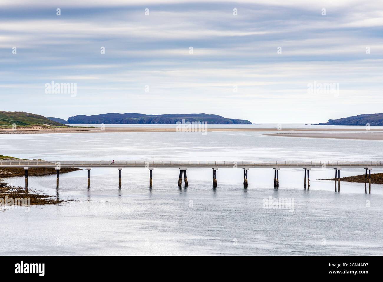 Un ciclista solitario attraversa il ponte Kyle of Tongue sulla A838, parte della Scozia NC500, con Tongue Bay e l'isola Eilean Nan Ron oltre di loro. Foto Stock