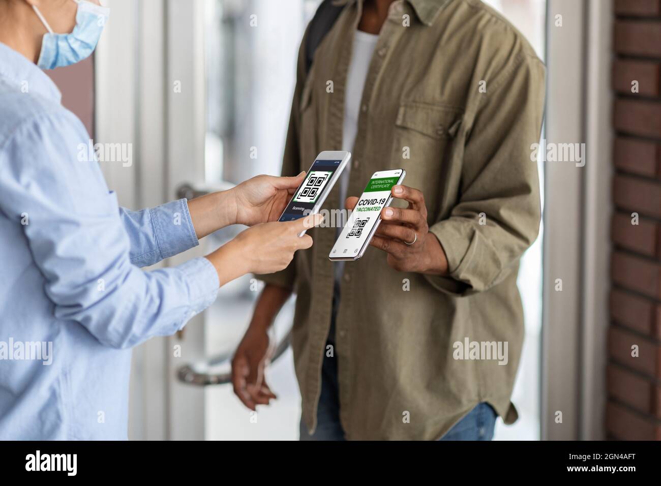 Controllo Covid-19. Worker Scanning Health Codice QR del visitatore nero all'ingresso Foto Stock