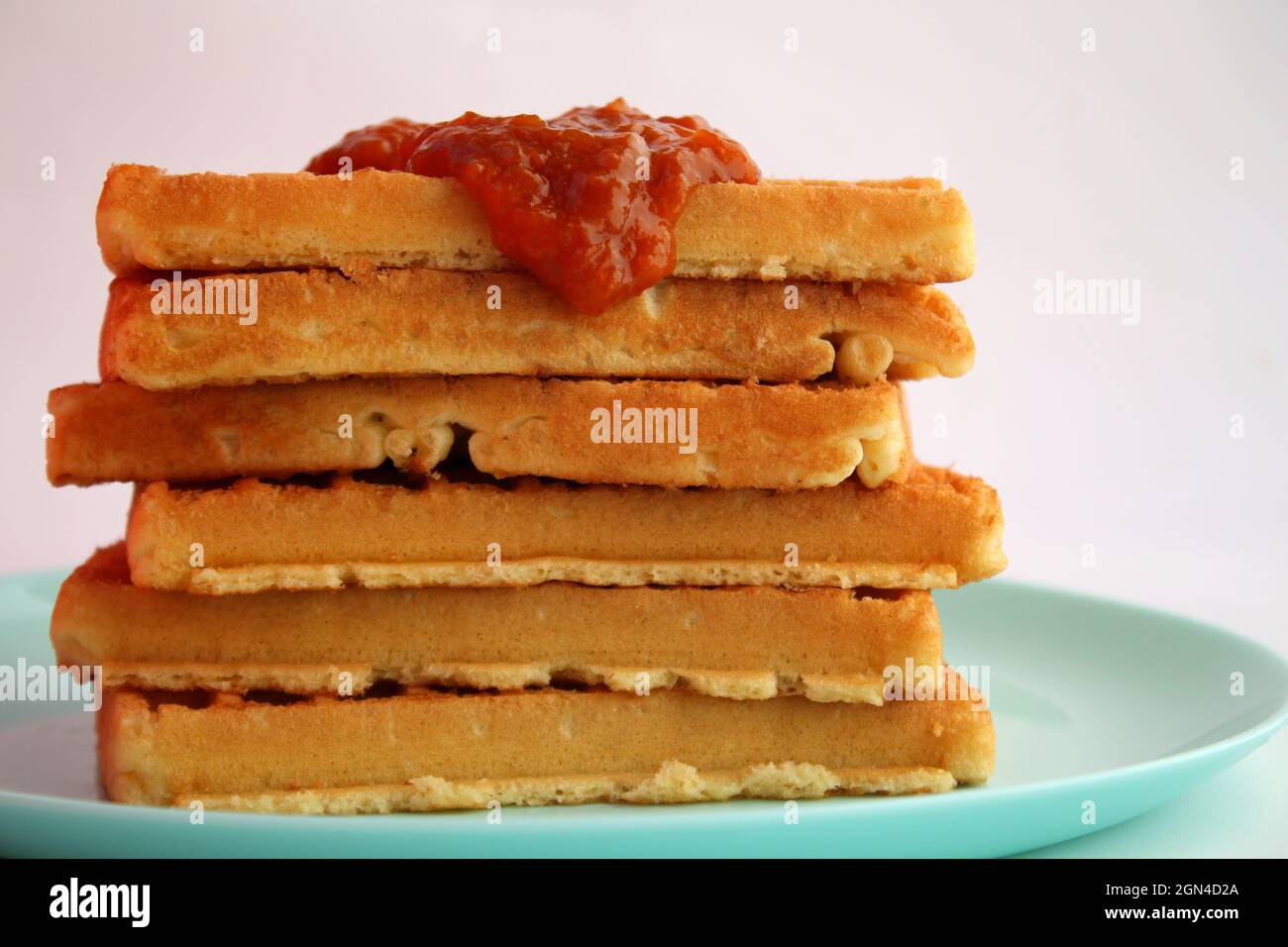 Waffle belgi con marmellata di albicocche su piatto turchese Foto Stock
