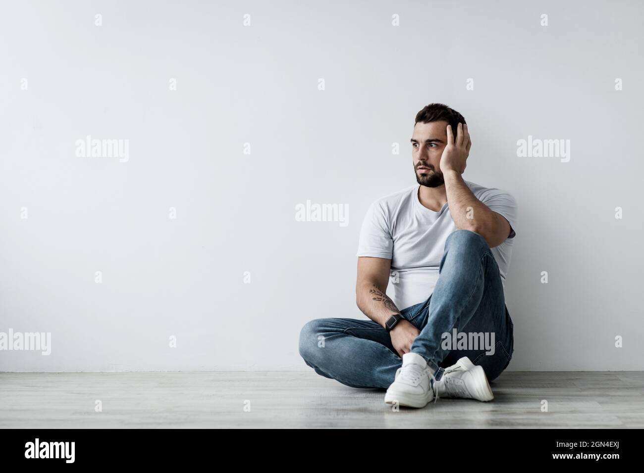 Triste depressione infelice pensivo giovane europeo attraente uomo seduta a pavimento Foto Stock
