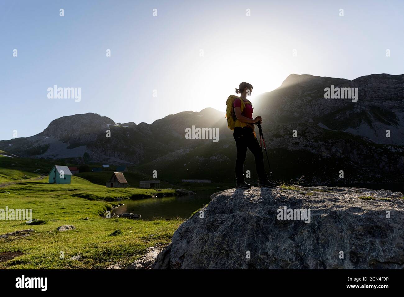 Donna escursionista in piedi sulla roccia presso il bellissimo lago Kapetanovo al tramonto, il Lago del Capitano tra le montagne sopra la città niksic in montenegro Foto Stock
