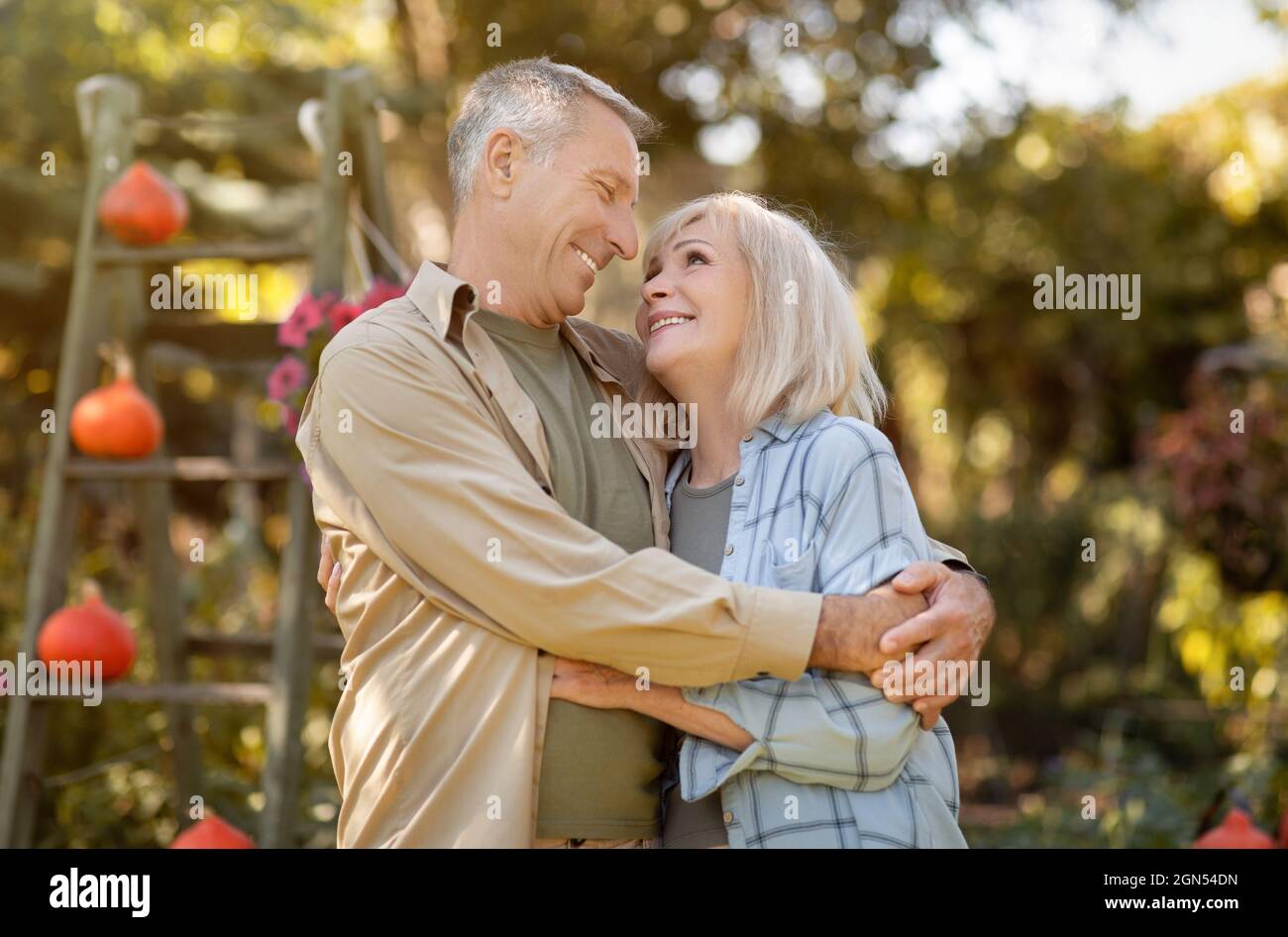 Buone spose anziane che amano abbracciare, camminare in giardino e godersi calde giornate autunnali, trascorrere del tempo all'aperto Foto Stock