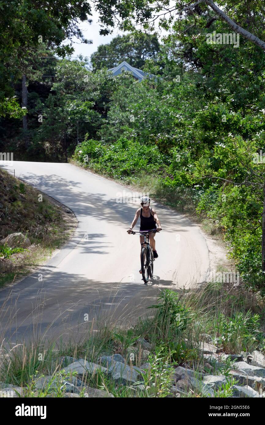 Donna che guida una bicicletta lungo una strada di campagna. Foto Stock