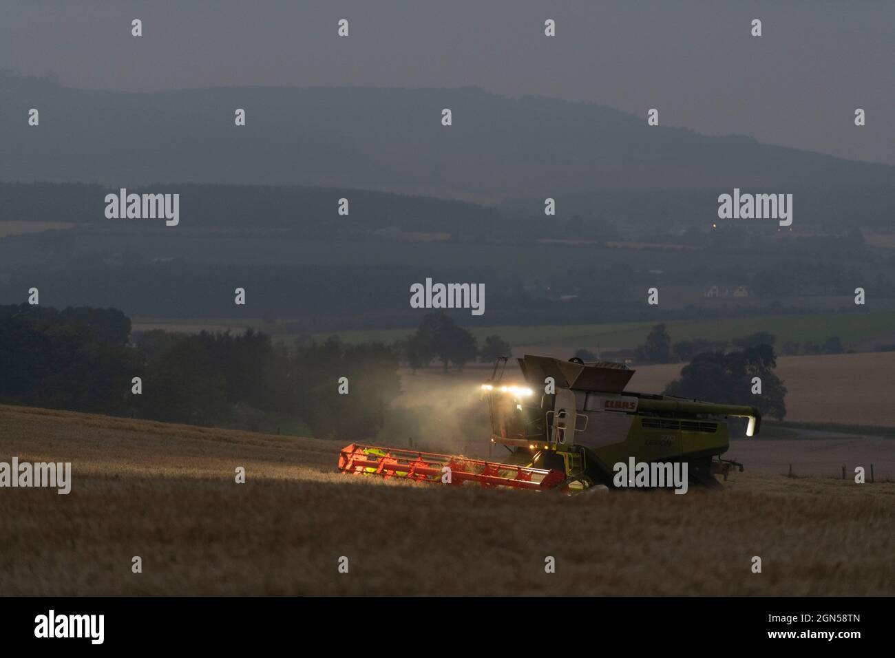 La campagna dell'Aberdeenshire dopo il tramonto con una Claas Lexion 770 mietitrebbia Harvester Harvesting un campo di Barley Foto Stock