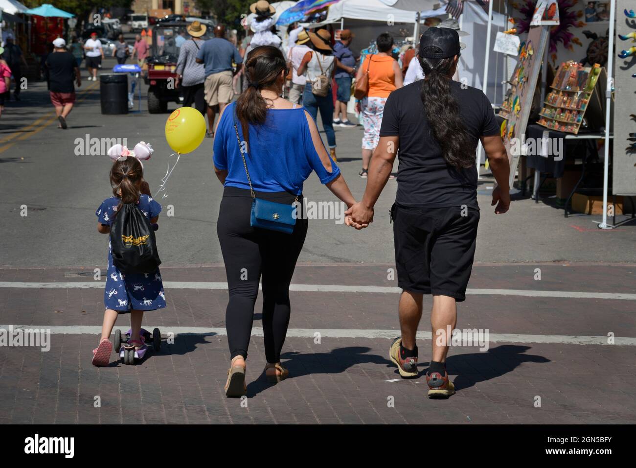Una coppia tiene le mani mentre camminano con la loro figlia giovane all'annuale Fiesta de Santa Fe a Santa Fe, nuovo exico. Foto Stock