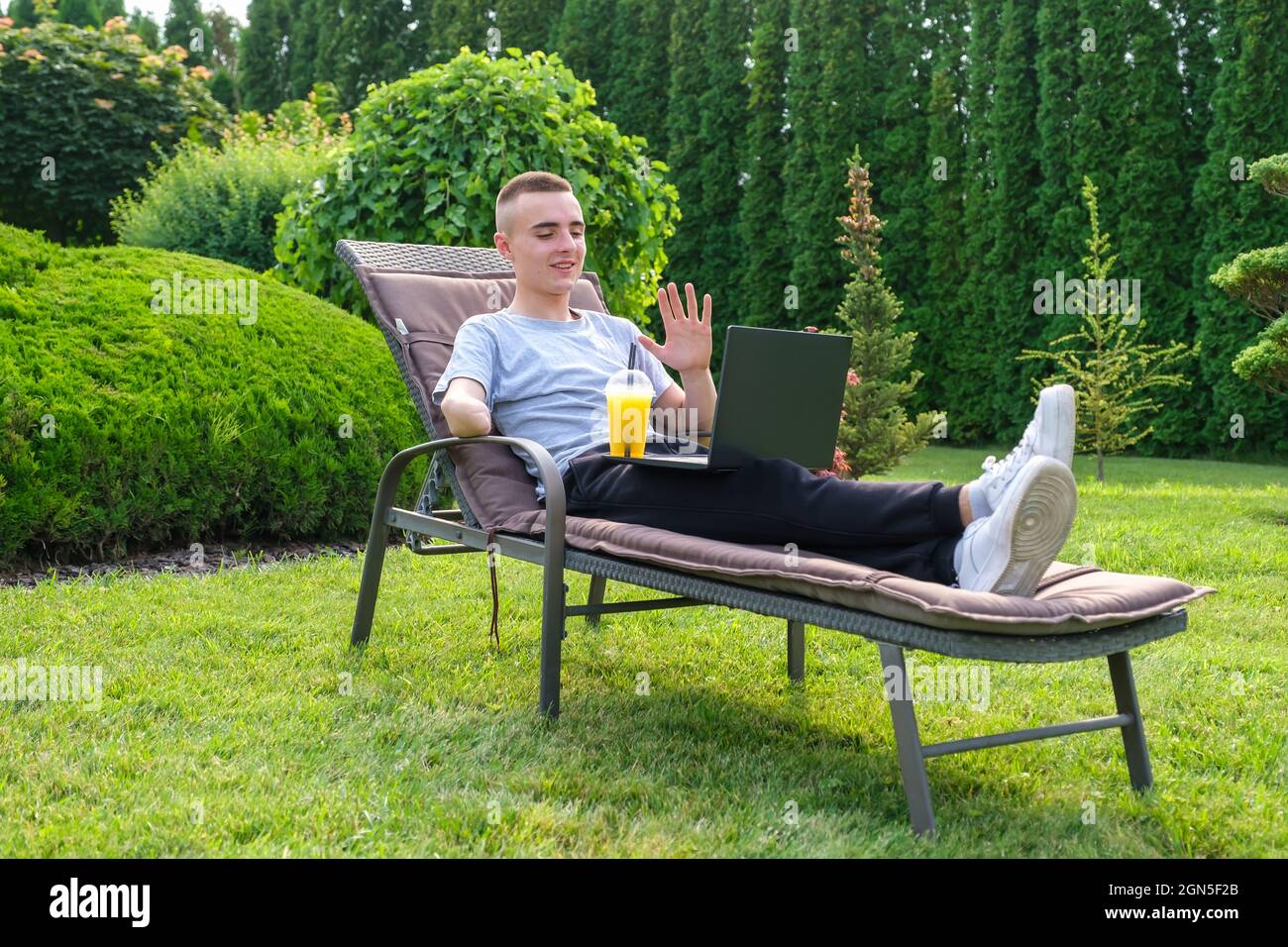 Uomo con braccio amputato beve un cocktail e parla con gli amici tramite il computer portatile Foto Stock