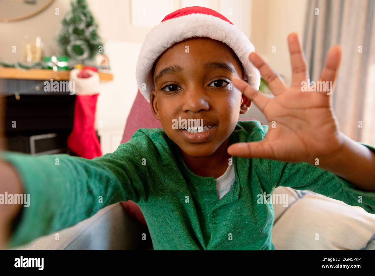 Ragazzo afroamericano che indossa il cappello di santa facendo videochiamata al tempo di natale Foto Stock
