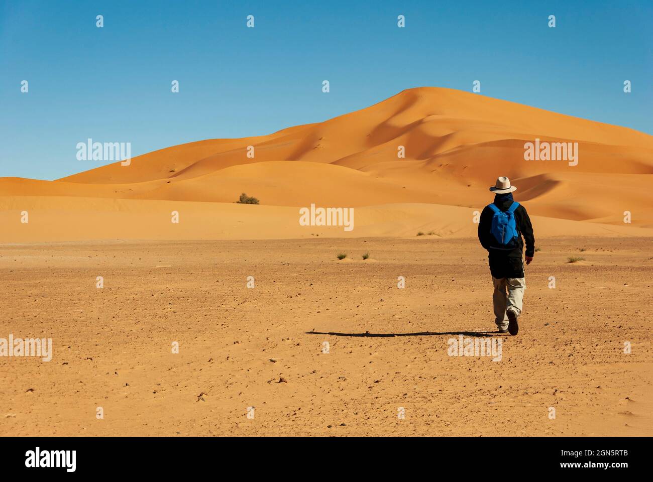 uomo che cammina verso le dune del deserto Foto Stock
