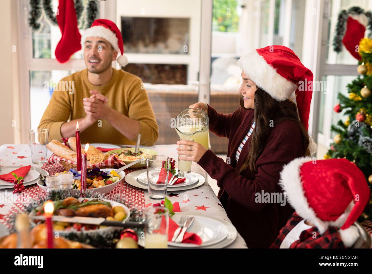 Famiglia caucasica che indossa cappelli di santa che hanno pasto di natale Foto Stock