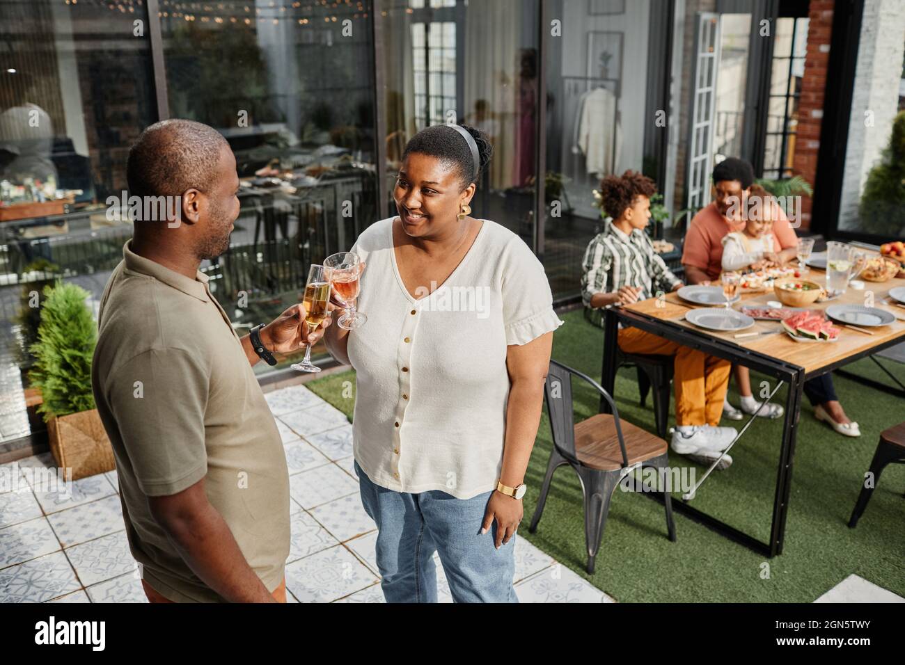 Ritratto di coppia afro-americana adulta godendo di bevande sulla terrazza all'aperto durante la riunione di famiglia, spazio copia Foto Stock