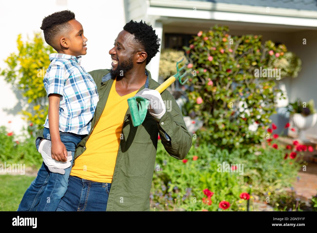 Felice padre afroamericano che tiene suo figlio e pitchfork Foto Stock