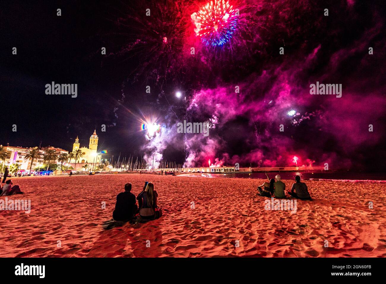 Sitges, Spagna. 22 settembre 2021. Gli spettatori si riuniscono in una spiaggia per seguire la tradizionale esposizione di fuochi d'artificio presso la chiesa 'San Bartolomeu' durante la 'Festa maggiore' di Sitges, 'Santa Tecla'. L'edizione della corona di quest'anno ha assunto una forma molto ridotta lasciando la spiaggia quasi vuota. Credit: Matthias Oesterle/Alamy Live News Foto Stock