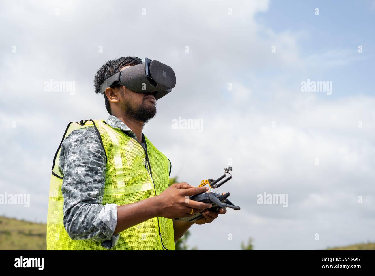 Pilota professionista di droni che controlla il drone osservando le cuffie per realtà virtuale utilizzando il telecomando - concetto della moderna tecnologia di sorveglianza Foto Stock