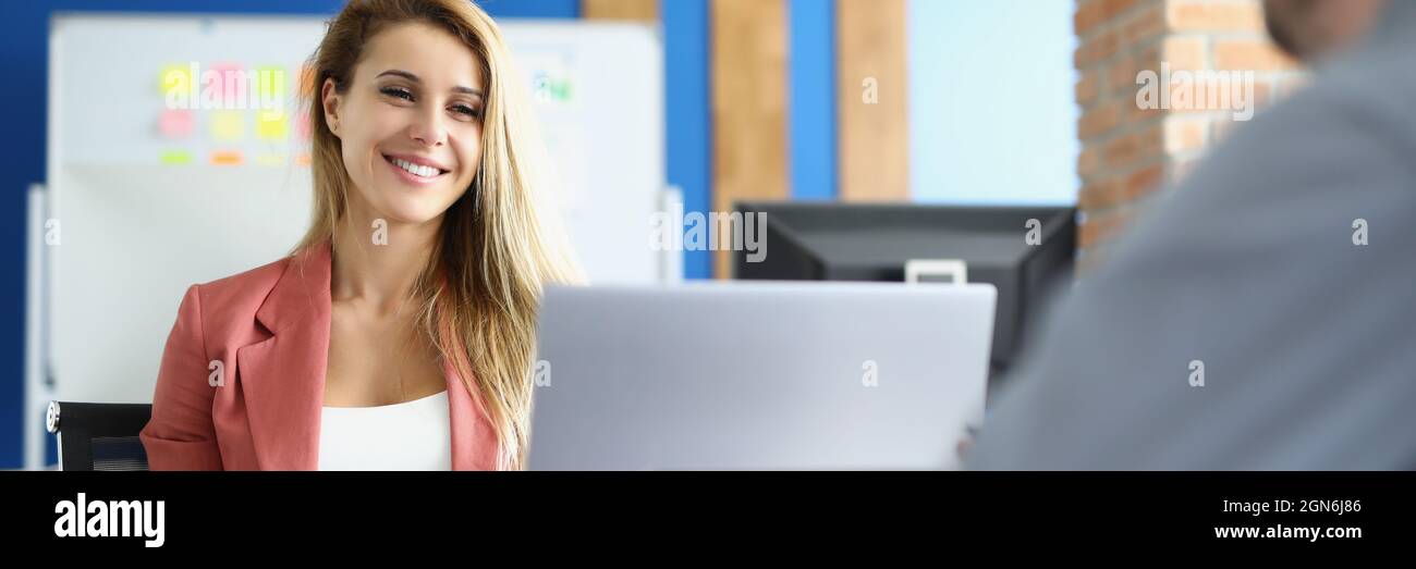 Donna d'affari sorridente comunica con il suo collega maschile al lavoro Foto Stock