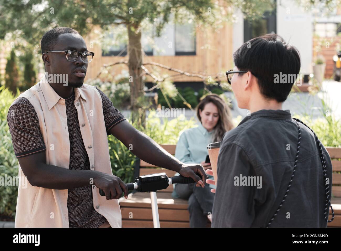 Ritratto orizzontale medio di giovane afroamericano uomo e donna asiatica che corre l'uno dentro l'altro all'aperto in piedi nel parco e che ha una piccola conversazione Foto Stock