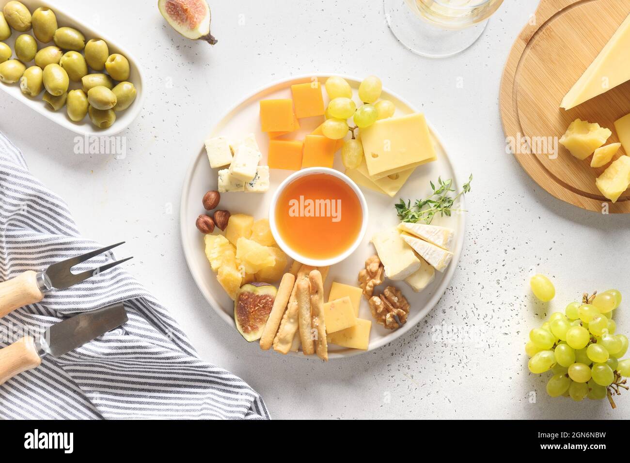 Piatto di formaggi con diversi formaggi e frutta su sfondo bianco. Vista dall'alto. Antipasto per la festa. Foto Stock
