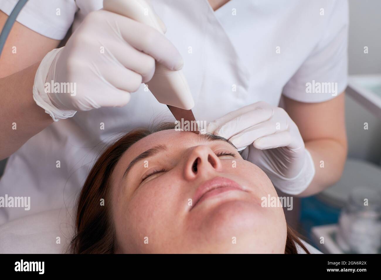 La pulizia ultrasonica del viso è una procedura di pulizia profonda del viso moderna e sicura. Donna alla reception presso l'estetista durante le procedure termali. Foto Stock