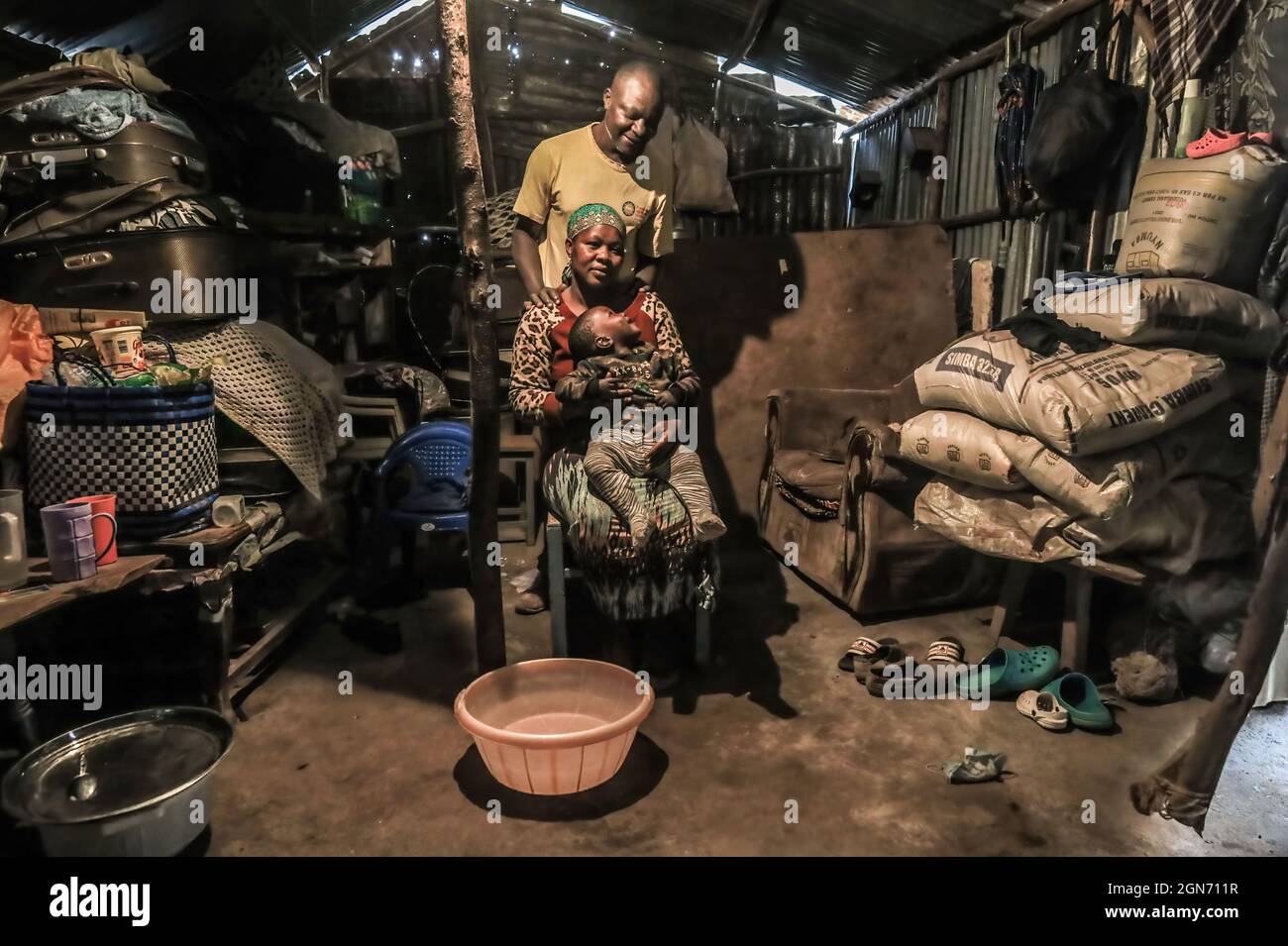 Charles Owigo (43) un membro del mestiere africano dell'osso prende una posizione con la sua famiglia alla sua casa nelle baraccopoli di Kibera, Nairobi. Un gruppo di artigiani dal mestiere africano dell'osso nelle baraccopoli di Kibera di Nairobi sta usando le ossa animali riciclate, corna e metalli di ottone per creare gioielli fatti a mano e decorazioni che sono poi venduti ai locali e turisti che a volte visiterebbero il laboratorio. Le ossa africane sono iniziate nel 2006 con un numero totale di 17 membri del gruppo che dipendono entrambi dal mestiere per vivere. Hanno continuato a lavorare nonostante le sfide affrontate dalla recente SA limitata Foto Stock