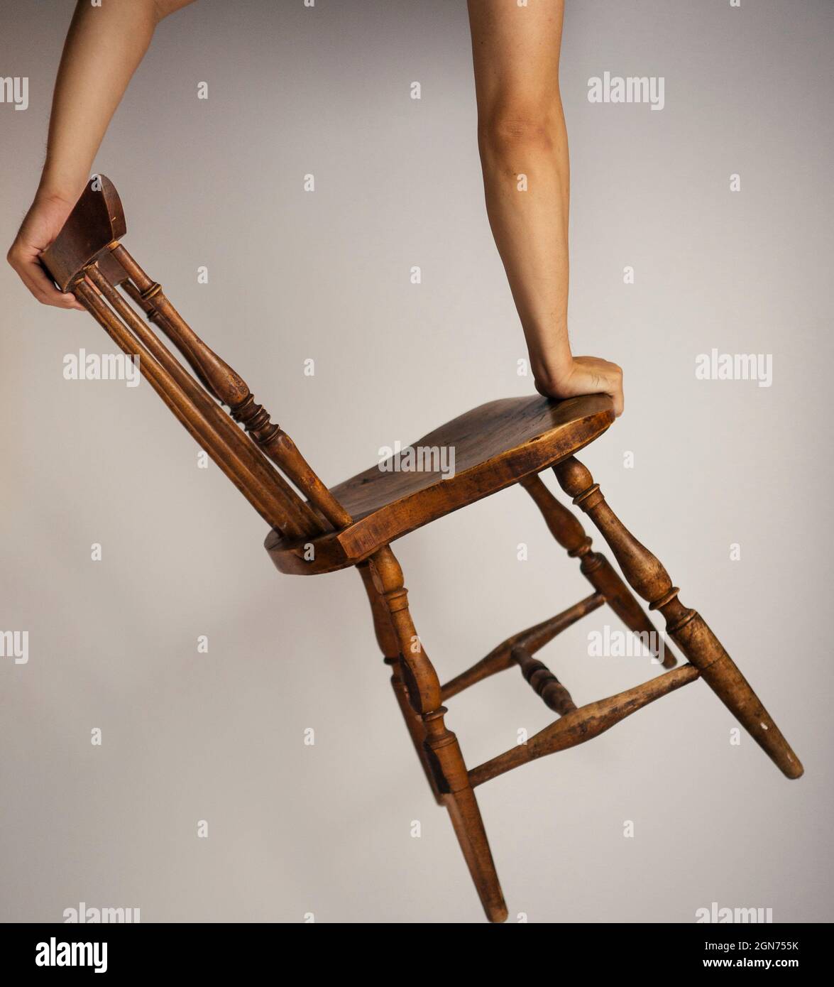 Cavalletto asiatico uomo bilanciamento su semplice sedia asiatica in legno Foto Stock