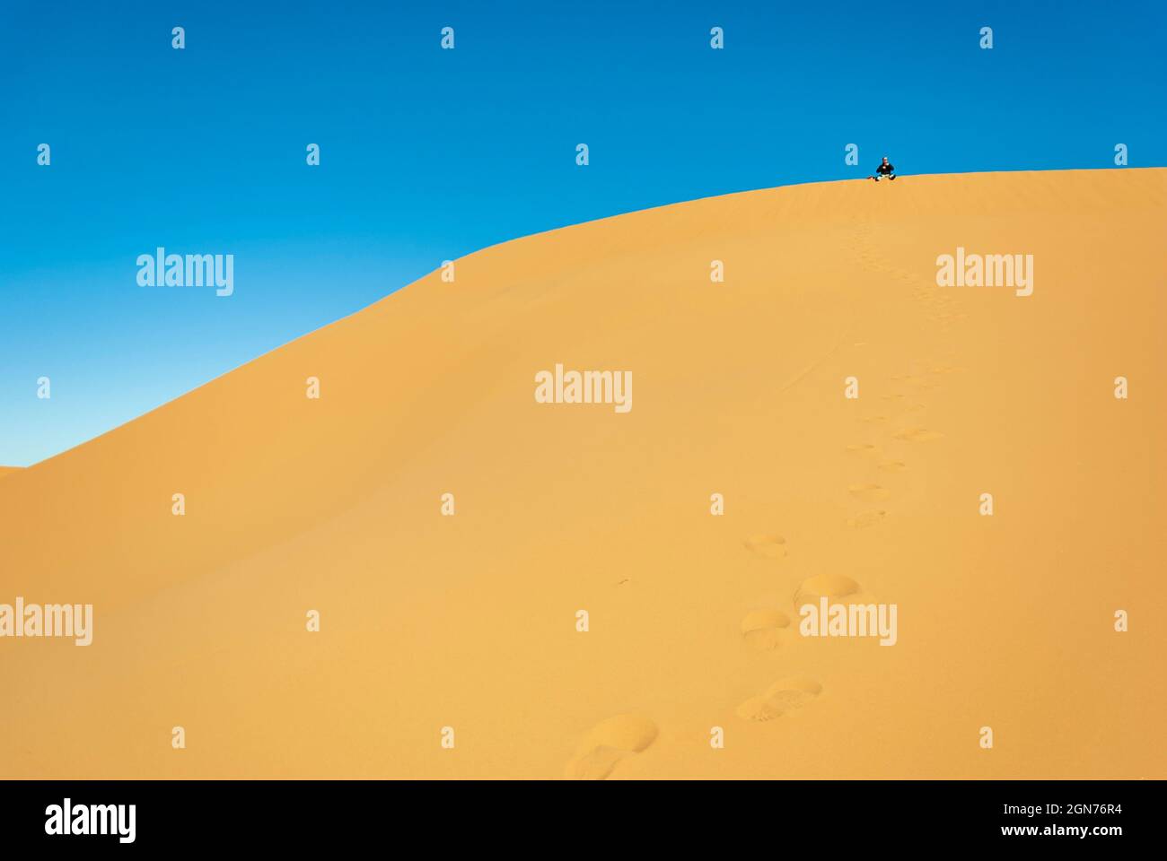 uomo che cammina nelle dune del deserto in una giornata di sole Foto Stock