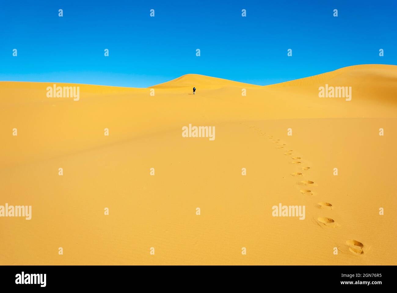 uomo che cammina nelle dune del deserto in una giornata di sole Foto Stock