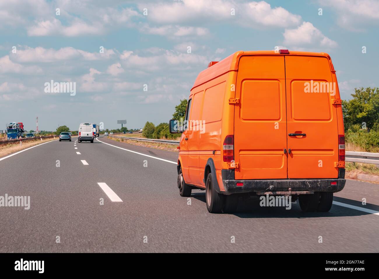 Minivan arancione su strada, industria dei trasporti e servizio di consegna Foto Stock