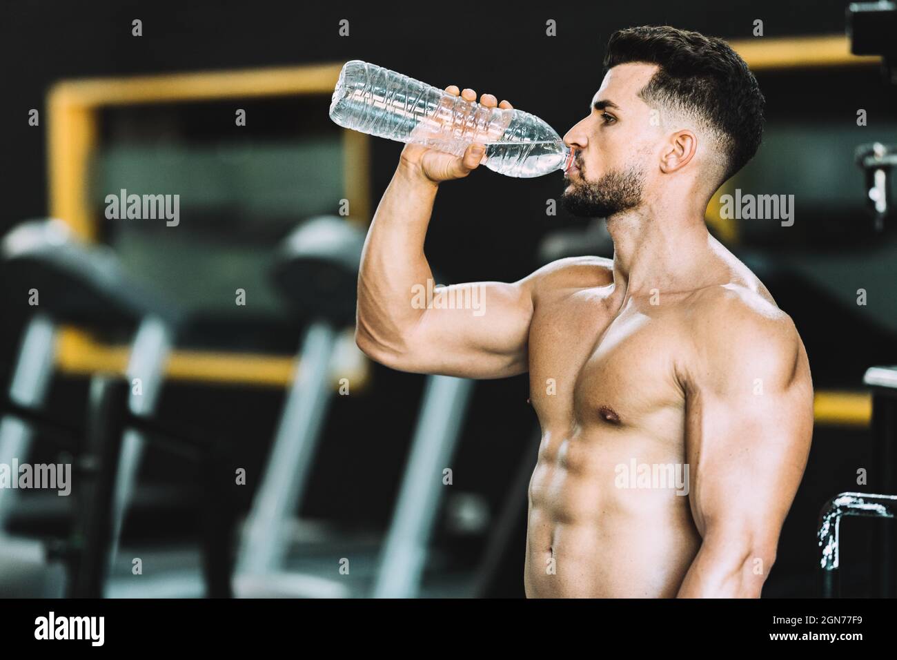 Foto con spazio copia di un forte uomo caucasico bere acqua in una palestra Foto Stock