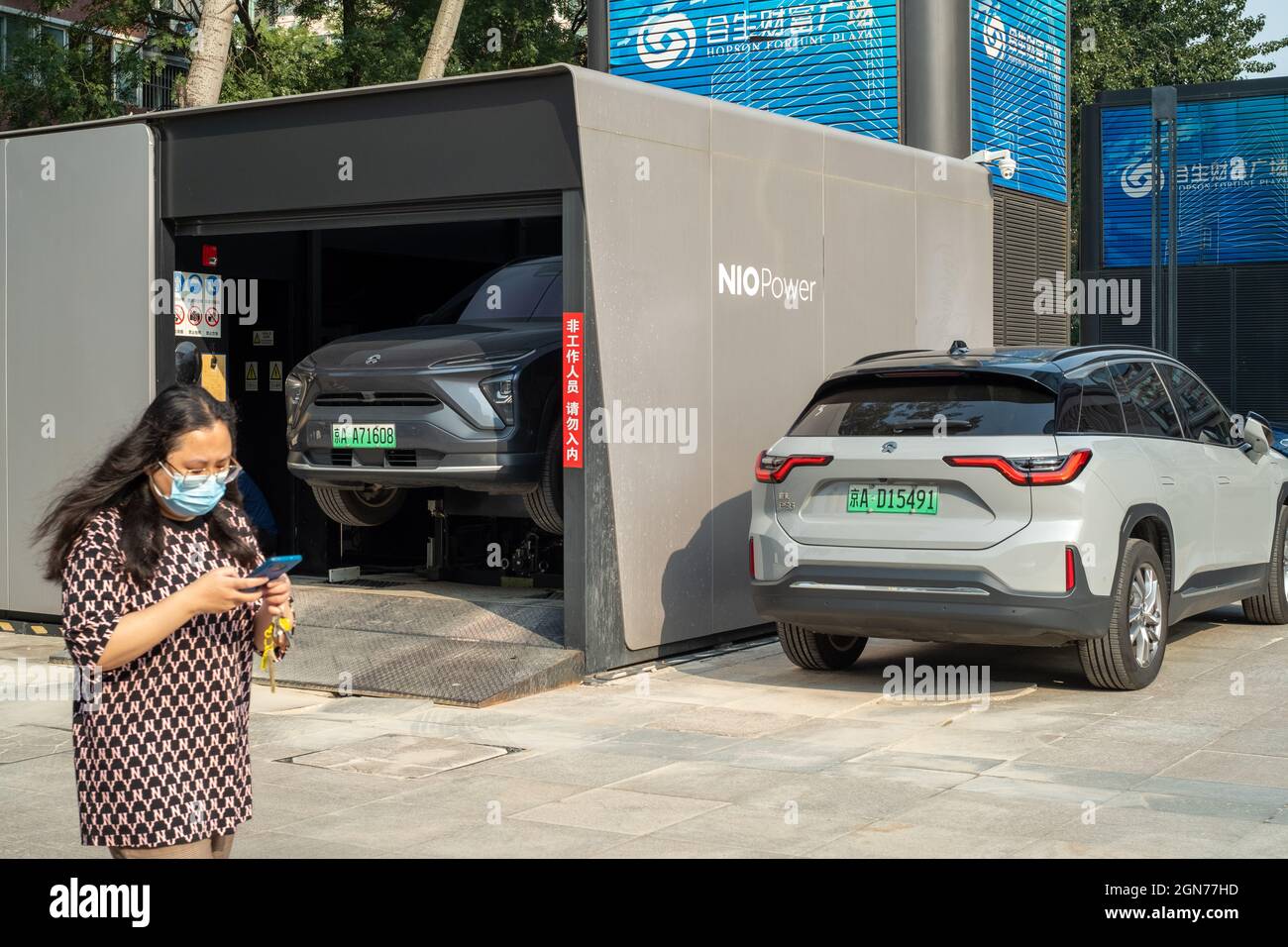 Una signora cinese passa accanto a una centrale elettrica NIO a Pechino, Cina. 23 settembre 2021 Foto Stock